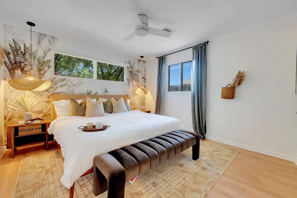 Airbnb bedroom with botanical wallpaper, sculptural lighting, and a white bed