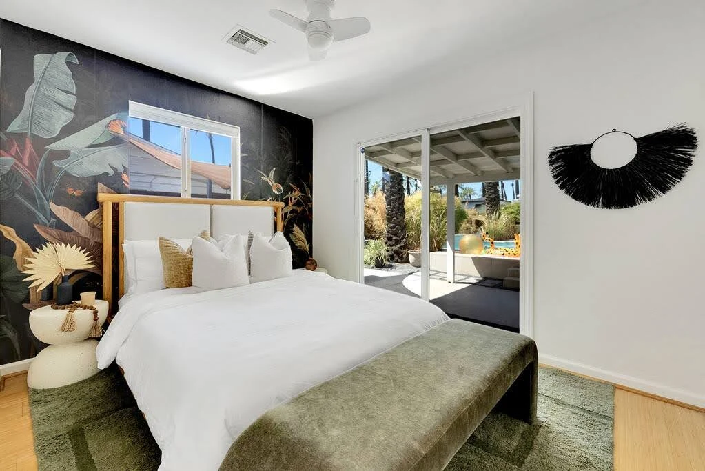 Bright Airbnb bedroom with leafy views, black accents, and a white upholstered bed