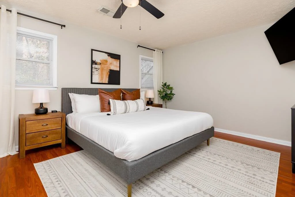 Simple Airbnb bedroom with a dark bed frame, wood nightstands, and neutral bedding