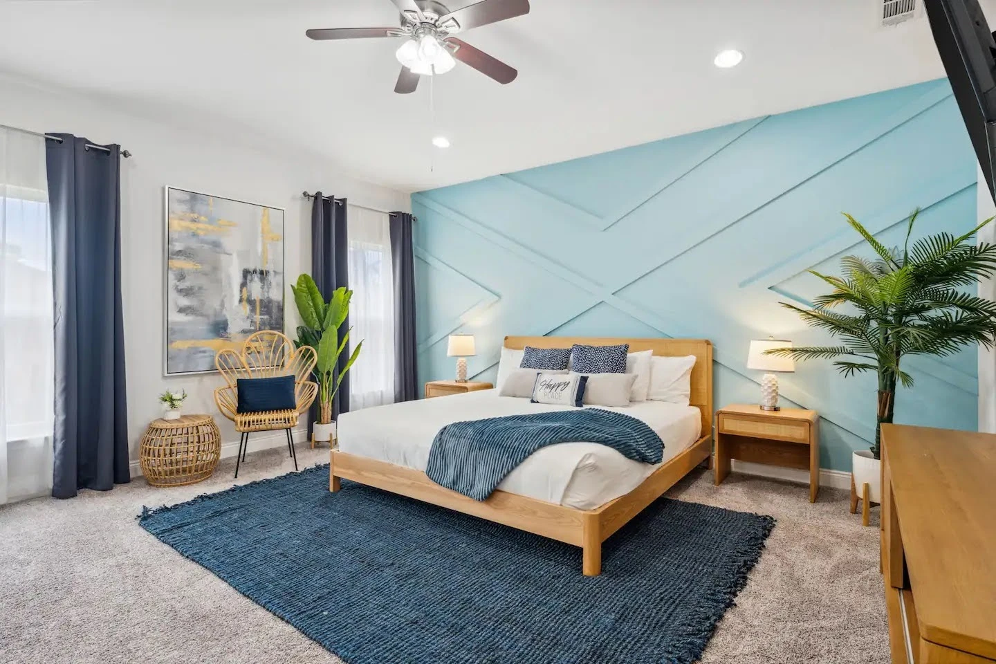 Coastal Airbnb bedroom with a blue feature wall, wood bed, and ocean-colored textiles