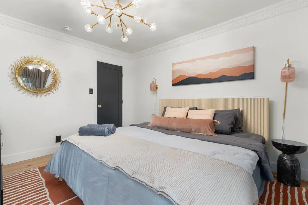 Classic Airbnb bedroom with a centered gray bed, matching lamps, and horizontal artwork