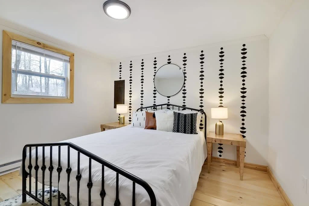 Minimal Airbnb bedroom with a black metal bed, pale walls, and simple wall decor
