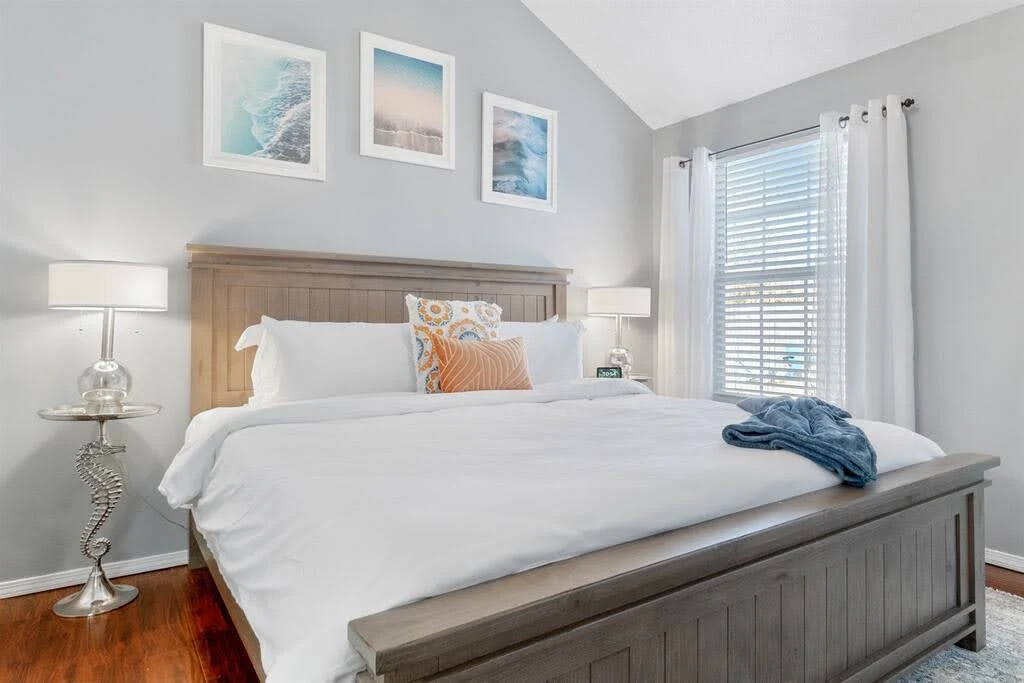 Airbnb bedroom with cool gray walls, white bedding, and pale wood bedside tables